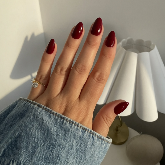 Hand with Instant Mani Co. Rogue Press on Nails wearing a gold ring, against a neutral background