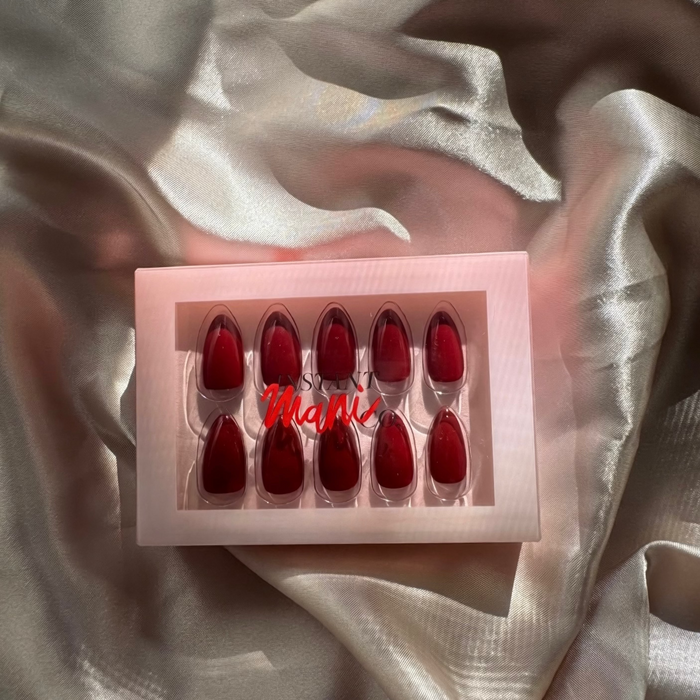 Set of rogue red Instant Mani Co. Press on nails  in a box on a textured fabric background