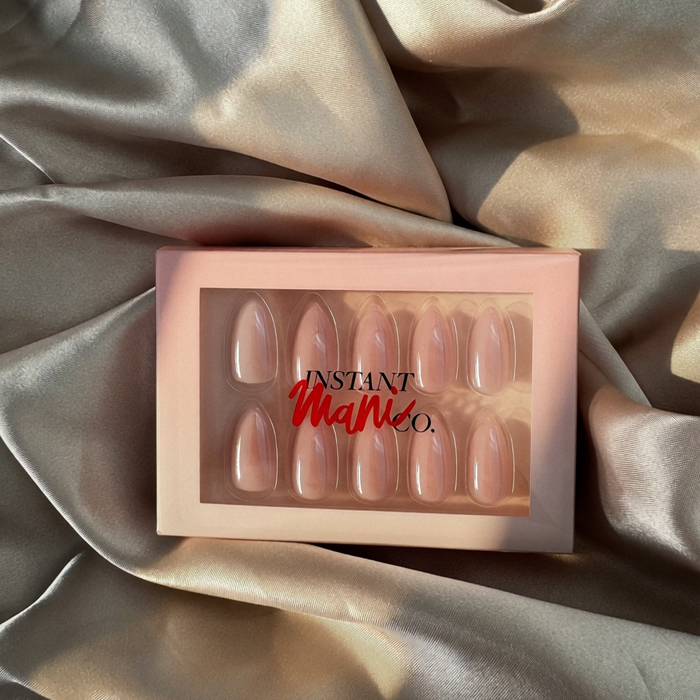 A set of 10 press-on nails in a pale pink shade, displayed inside a light pink box with the brand name 'Instant Mani Co.' printed on the front.