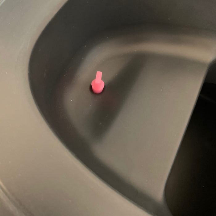 Nahaufnahme eines pinkfarbenen, kegelförmigen Objekts in einem grauen Behälter.